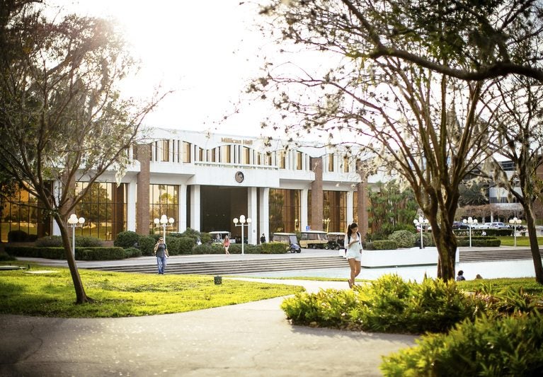 close up of students walking by millican hall and reflecting pond