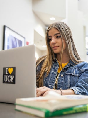 female ucf student working intently on laptop