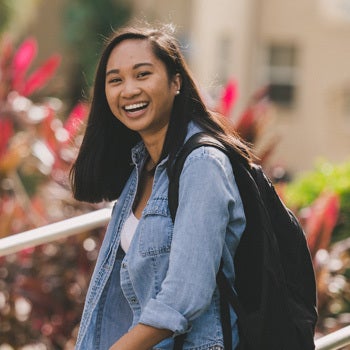 ucf student in denim jacket and backpack, smiling while looking at camera