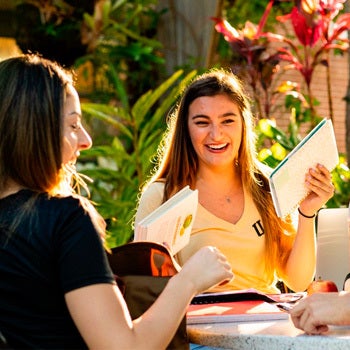 two students applying to ucf at an outside table while smiling