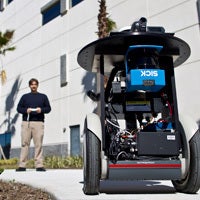 male ucf student in background, using remote control for robotics in foreground