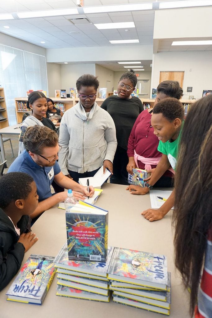 Laurence signs books for students. Mary, a 6th grader at ACE (center, in grey), is an aspiring author.