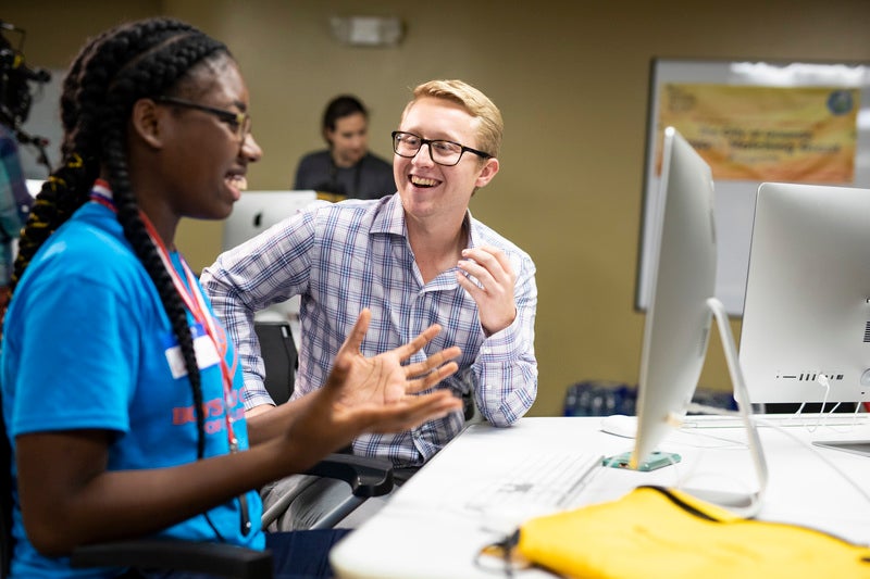 two ucf downtown students smiling in front of computer