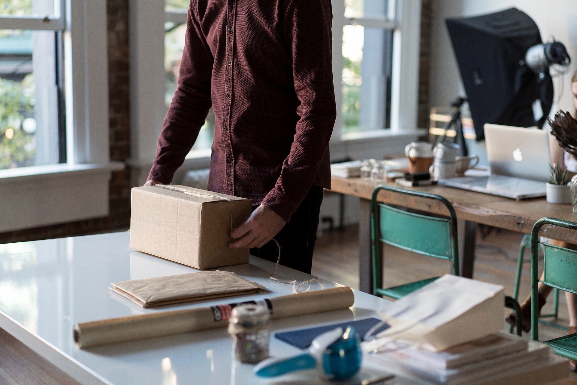 A person in a class room boxing up a package to be mailed.