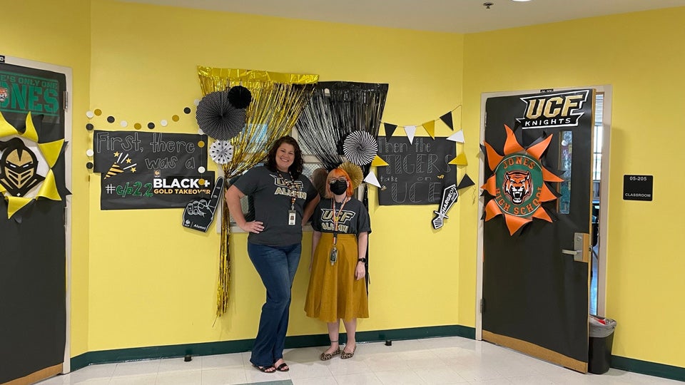 two employees in front of decorated wall