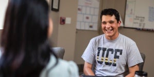 smiling ucf student sitting in financial aid office talking with another person