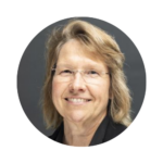 Alison Schultz, Program Manager I at UCF, smiling in a professional headshot. She is wearing glasses and a dark jacket, with shoulder-length light brown hair, posed against a dark gray background.