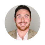 Austin Wilson, Manager of Public Affairs at UCF, smiling in a professional headshot. He is wearing a tan blazer with a white shirt and a UCF lapel pin, posed against a light gray background.