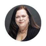 Sharon Whitley, Executive Assistant II at UCF, smiling in a professional headshot. She is wearing a black top and necklace, with long dark hair parted to the side, posed against a dark gray background.
