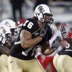 ucf football player, gold pants, black jersey, white helmet