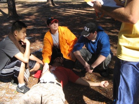 students simulating medical rescue while hiking