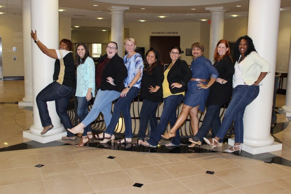 group of ucf staff From the Rosen College of Hospitality Management all facing to the left and kicking their left legs out