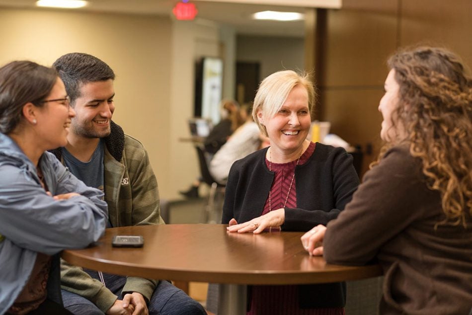 Pegasus Professor Honorees gathering around round wooden table laughing