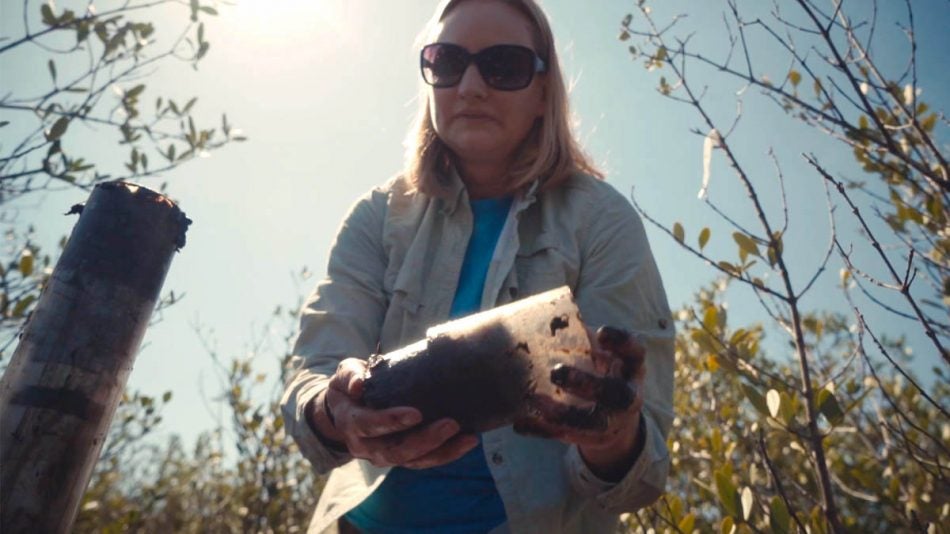 Assistant Professor of Biology Lisa Chambers collects a soil sample from the Merritt Island National Wildlife Refuge to help study wetland ecosystem changes over time.