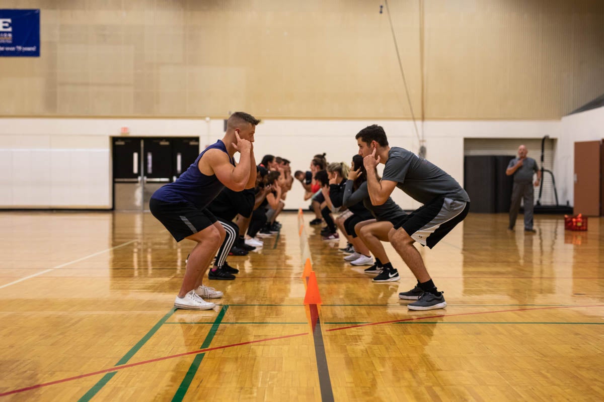 During a warm-up exercise, students test their reflexes by identifying pressure points on their bodies and competing against one another to see who grab a cone the fastest. 