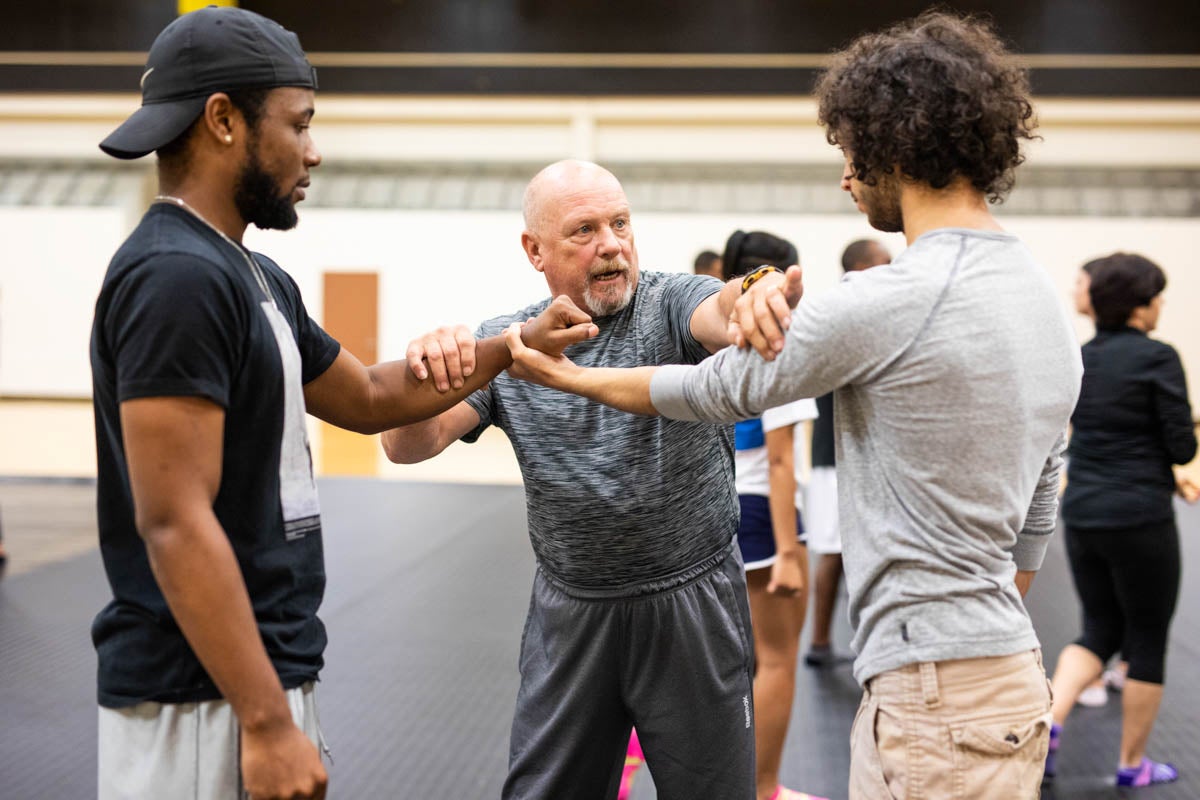 Technical assistant Mark Simpson works with two students to demonstrate how to break away from the hold of an attacker.