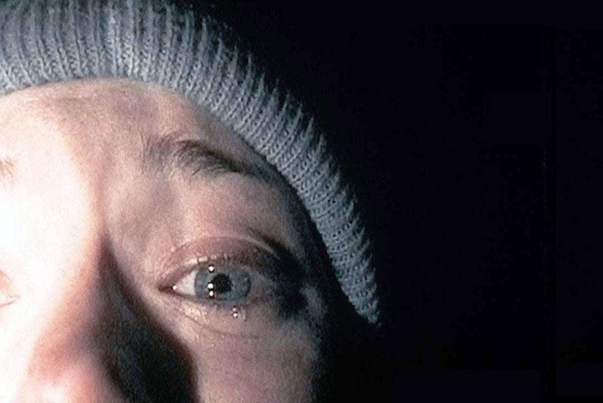 closeup of left side of a woman's face, wearing a blue beanie, at night illuminated by a flashlight
