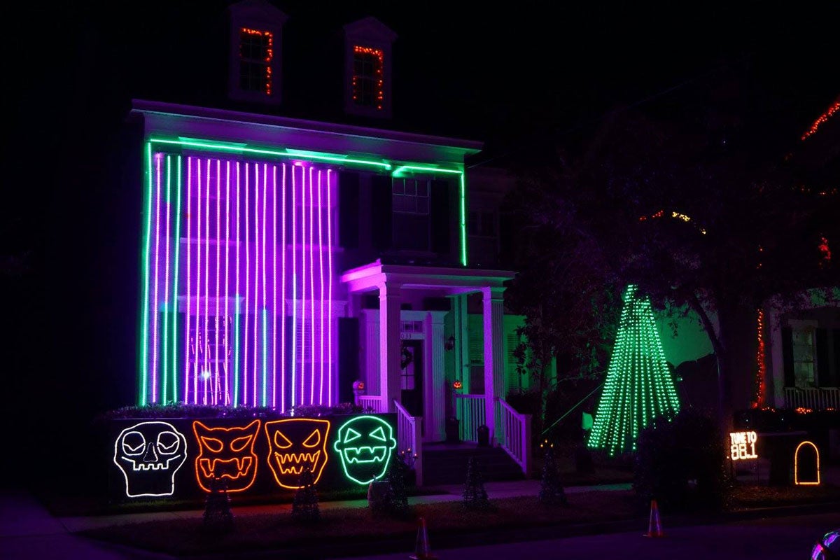 two-story home lit up at night by green and purple neon lights