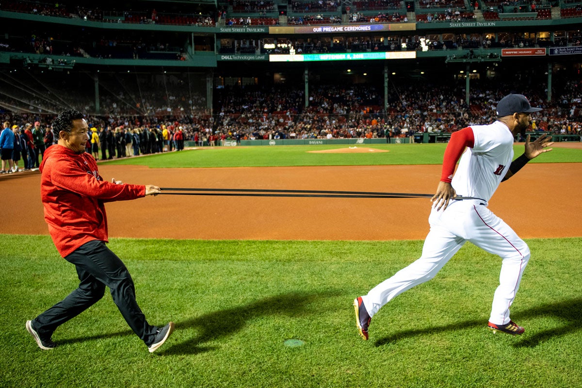 David Price of the Boston Red Sox runs with a long band around his waste with a man in a red sweatshirt and dark pants pulling behind him
