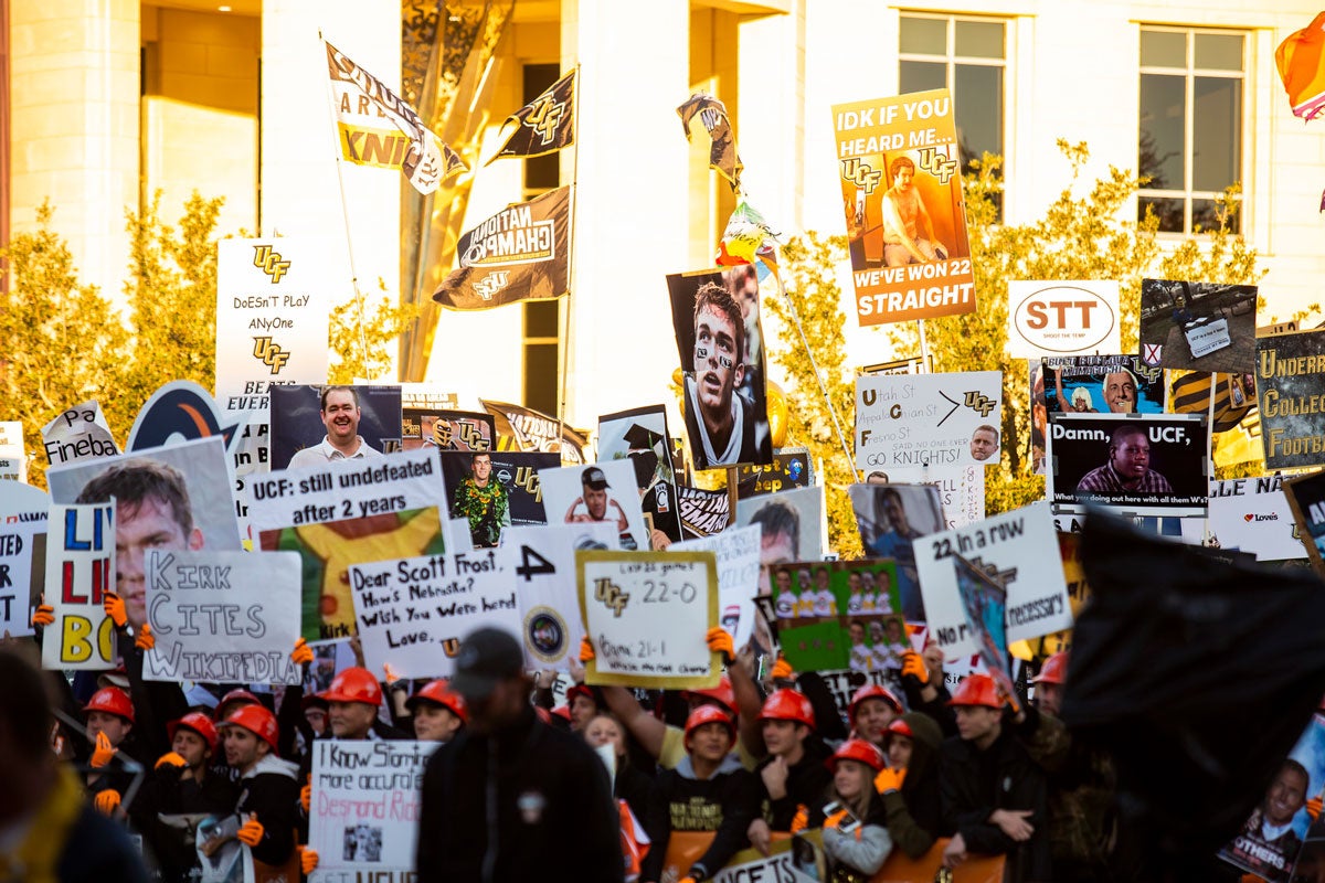 A sea of fans holding signs in front of a brick building