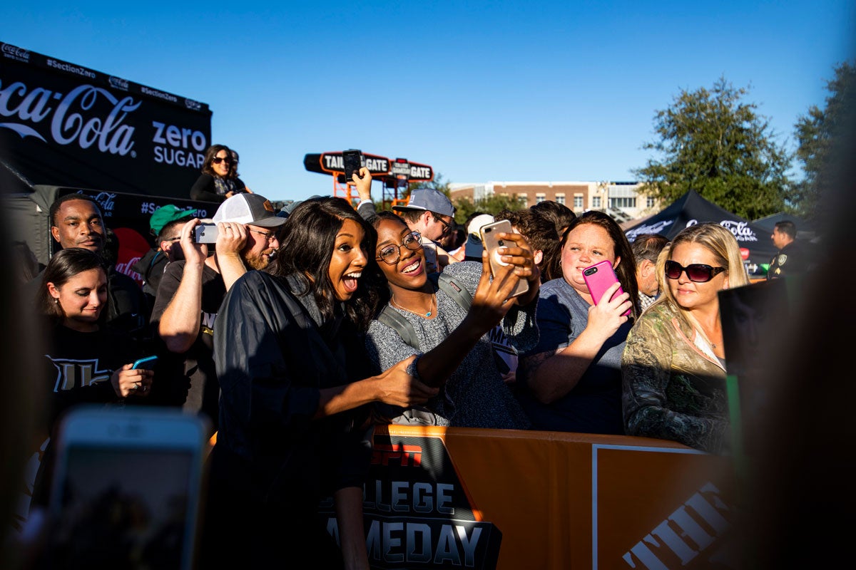 Two women pose for a selfie in a crowd outside