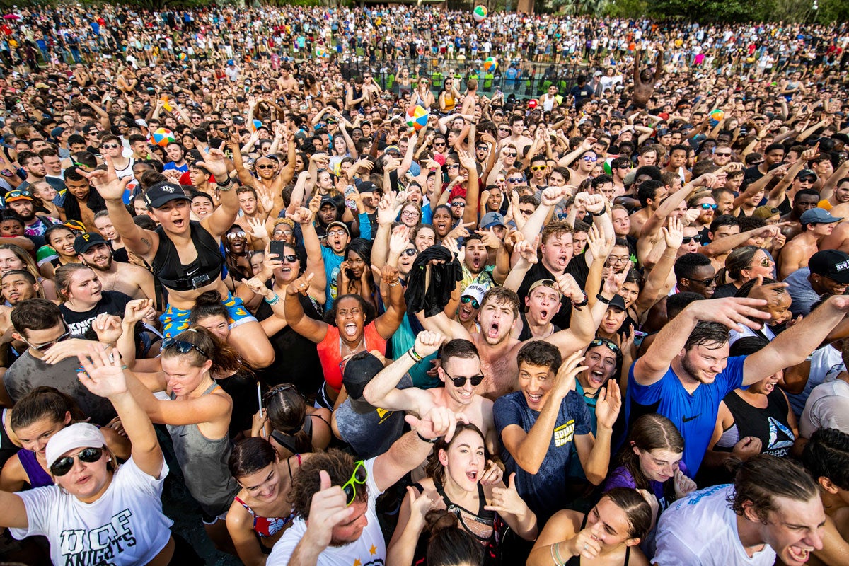 Hundreds of people in a crowd with their arms waving in the air cheering