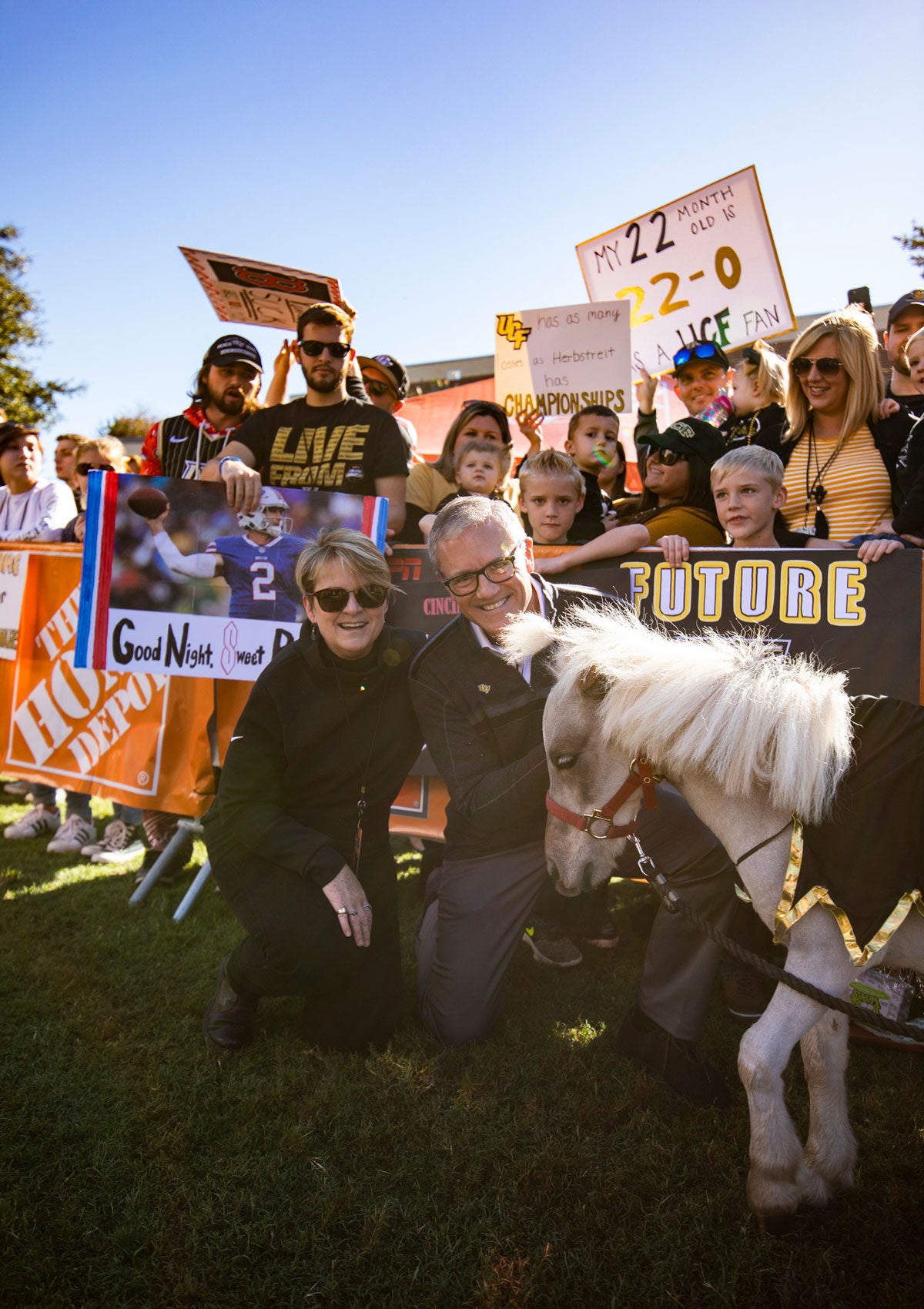 President Dale Whittaker and wife Mary kneel by mini horse Knugget in front of cheering fans