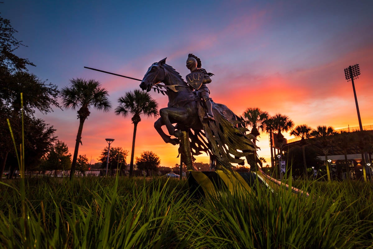 The sun rises over the Charging Knight statue outside of Spectrum Stadium.