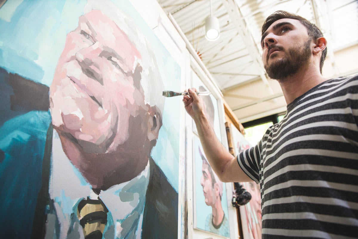 Studio art major John Currie '18 works on a special portrait of John C. Hitt to honor his 26 years of service as UCF's fourth president.