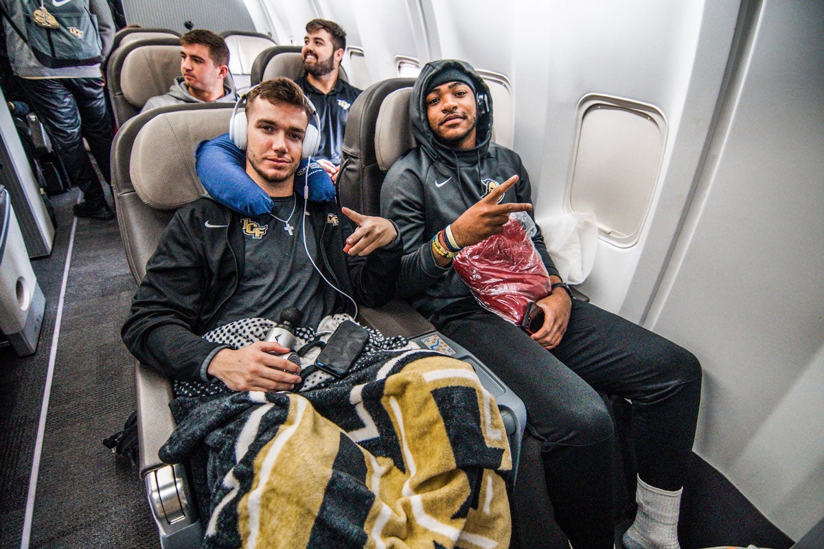 Two football players sit next to each other on a plane