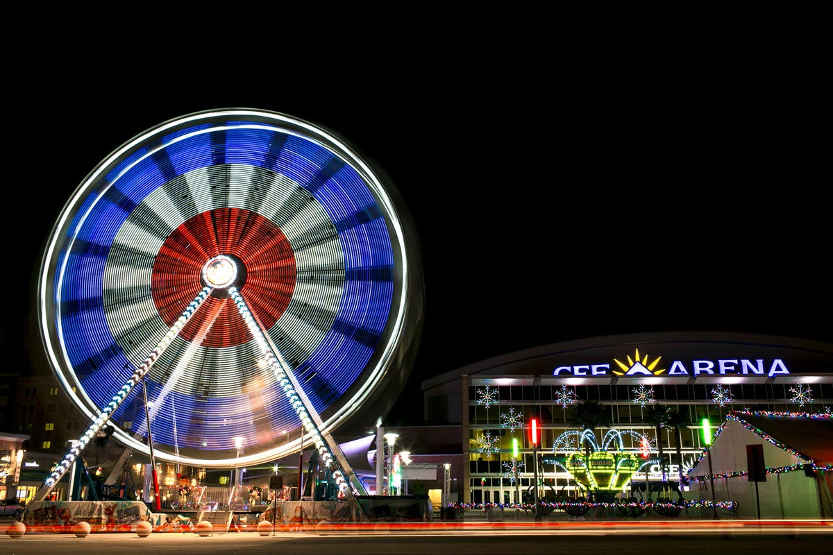 Ferris wheel spins at night with red white and blue colors and CFE Arena in the back ground