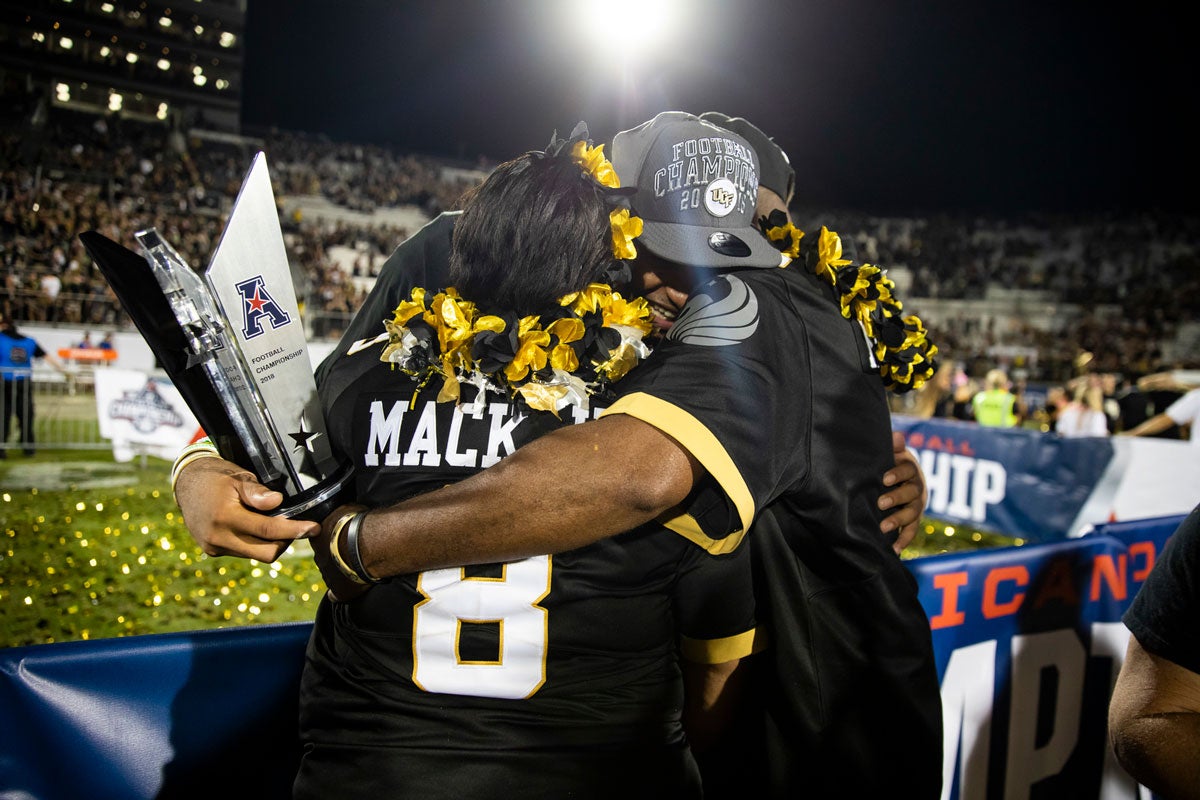 Darriel Mack hugs his parents while also holding a gray trophy