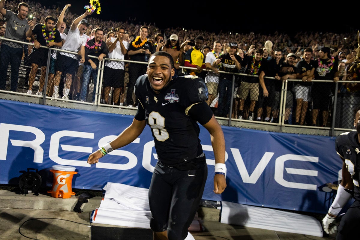 Darriel Mack wearing a black #8 jersey cheers in end zone with fans behind him in stands