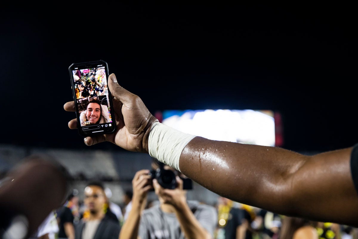 Closeup of an arm holding a phone with McKenzie Milton on screen