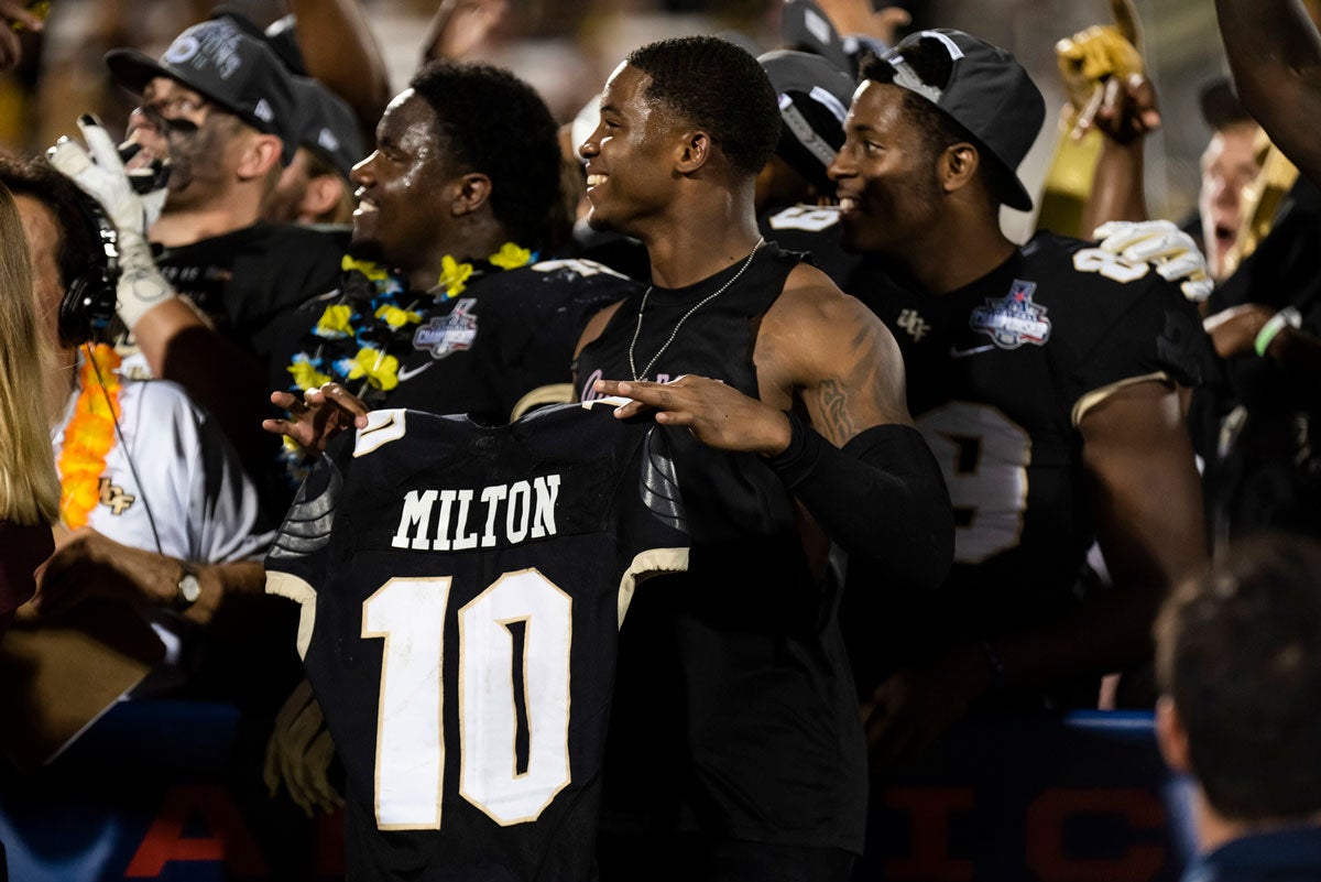 Football players hold #10 Milton black jersey