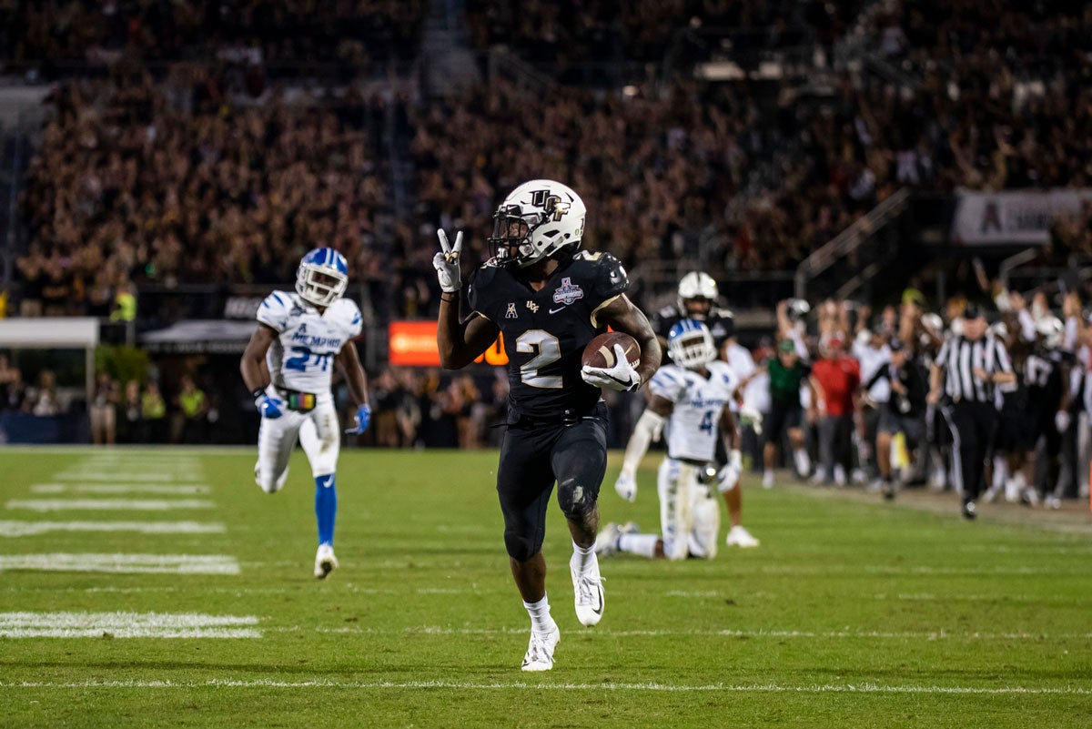 UCF running back Greg McCrae streaks down field holding #2 sign with his fingers as Memphis players chase him down field