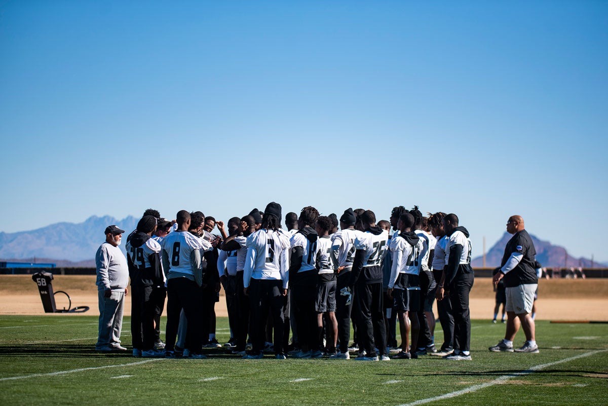 a group of football players huddles on the football field
