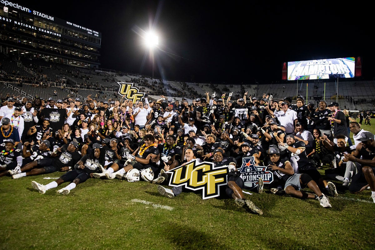 Football team poses with UCF signs on field