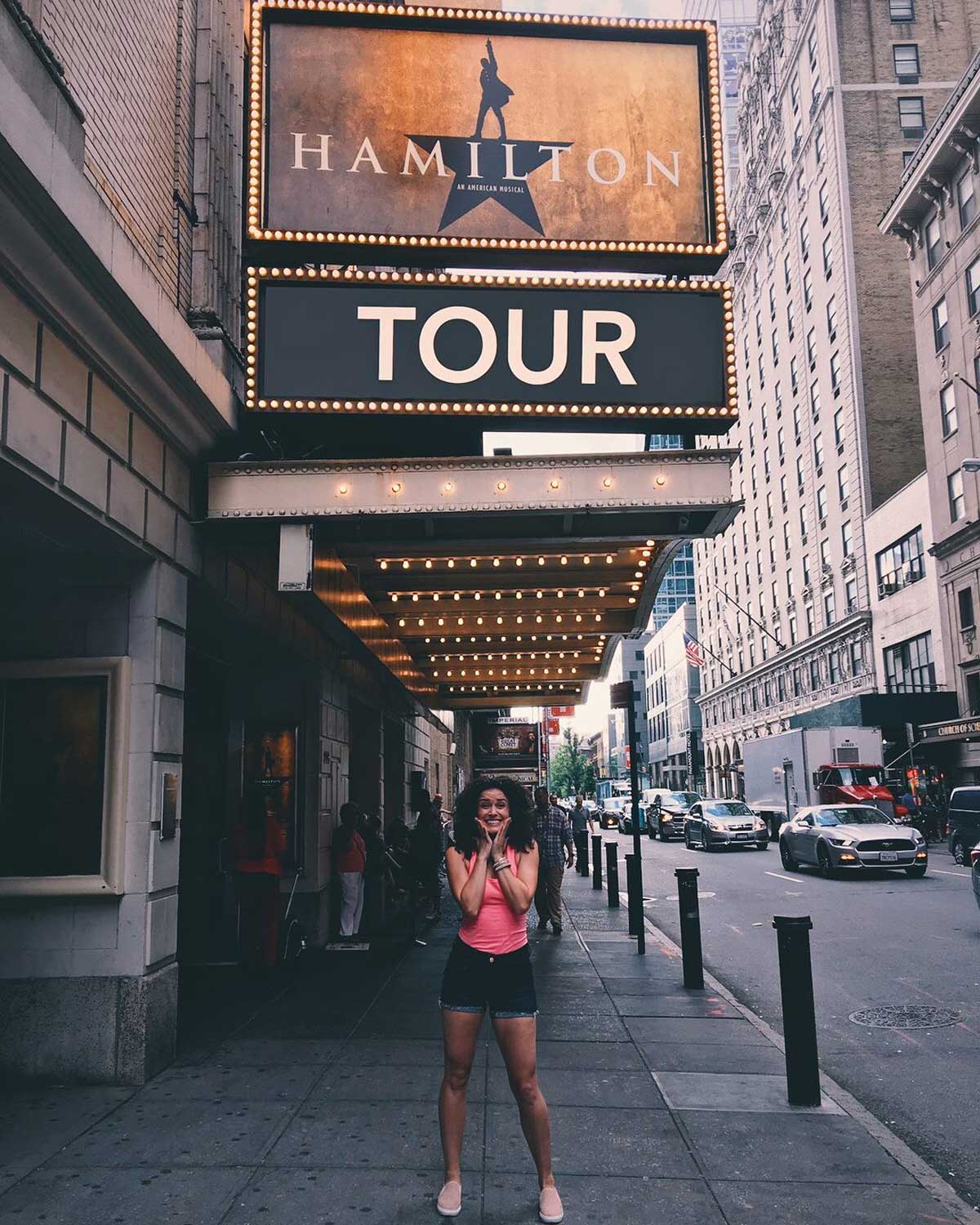 Woman stands under Hamilton theater marquee