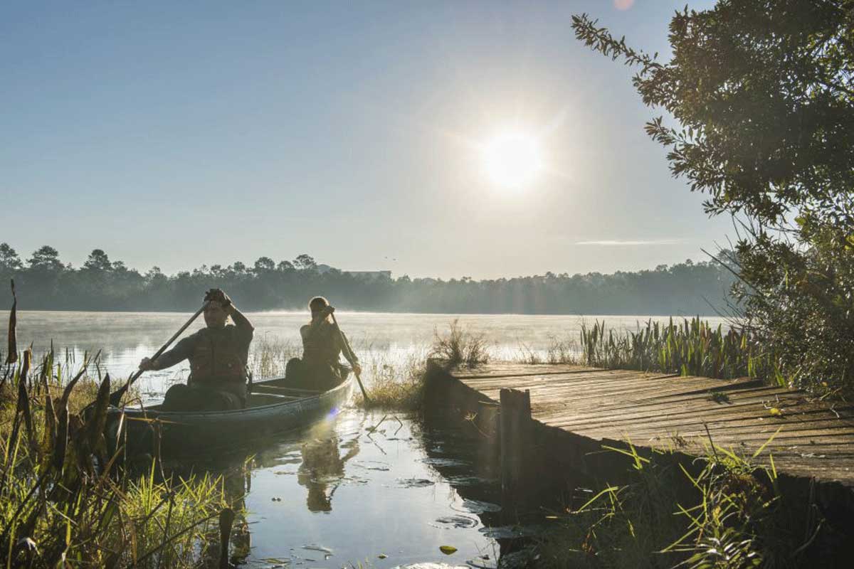 Two people in a canoe on a lake near a dock