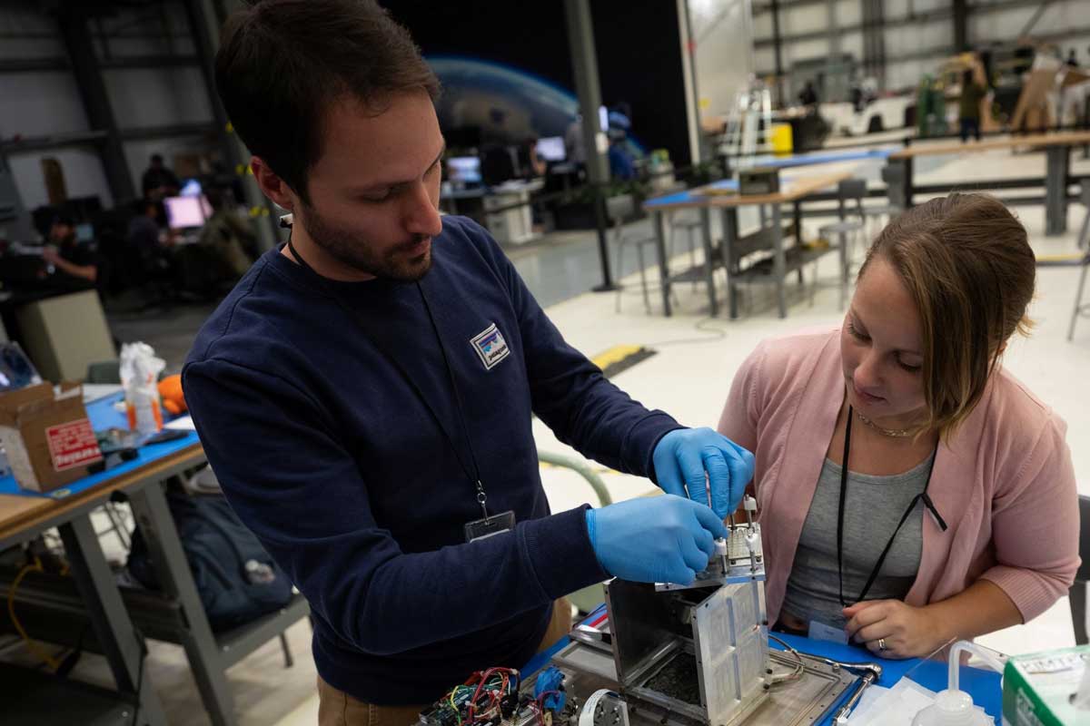 Man and woman examine box with wires