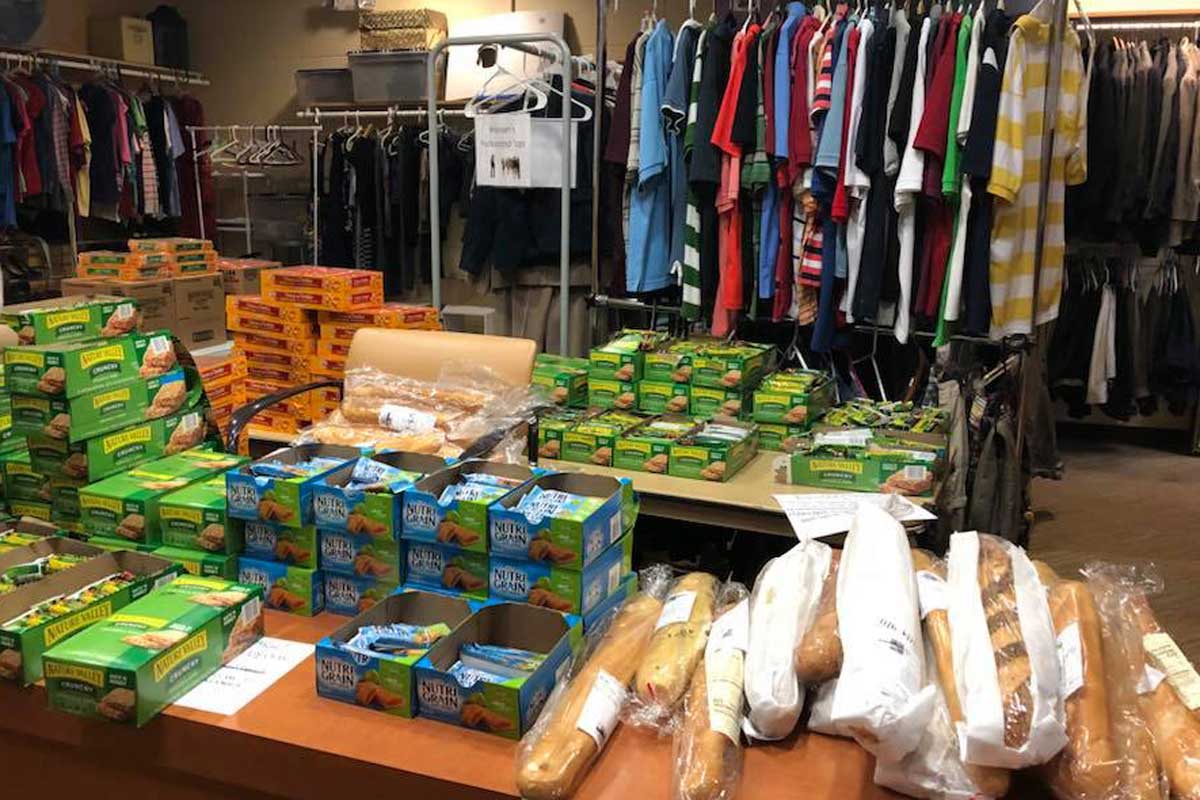 food stacked on a table in front of clothes hanging on a rack