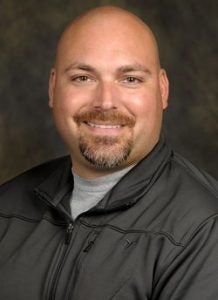 bald man with a goatee in a gray jacket