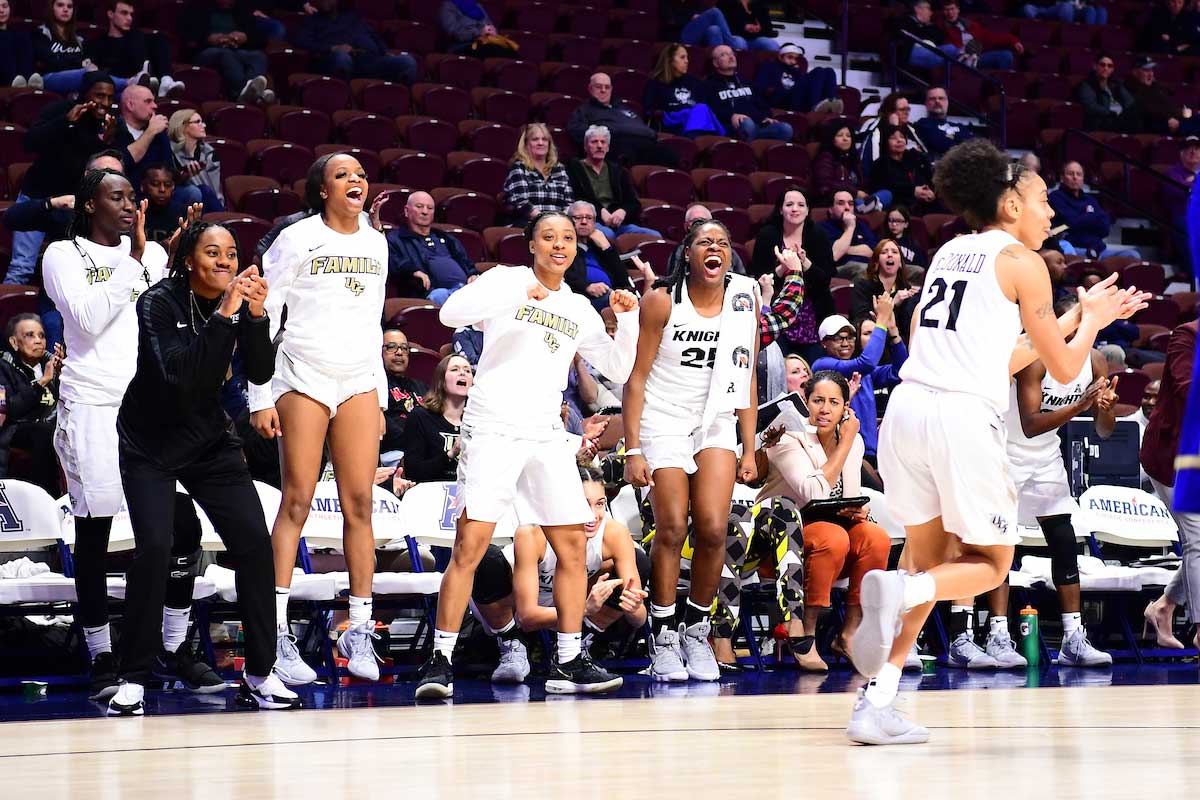 women's basketball players cheer on team bench