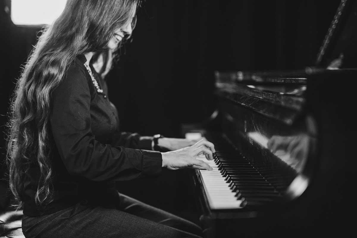 black and white photo of woman with long hair playing piano