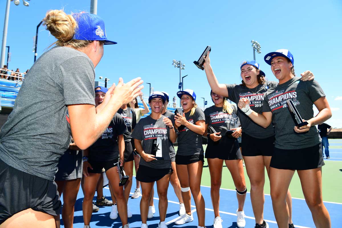 women's tennis team celebrates with trophies on court