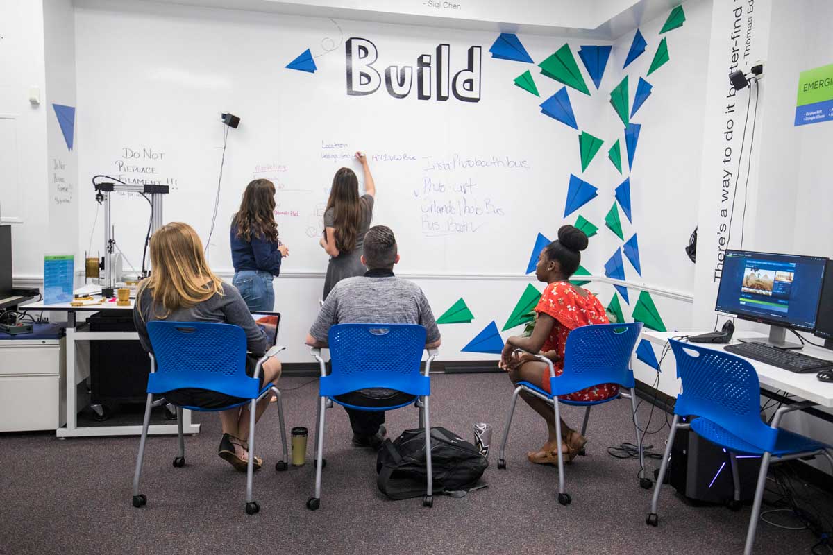 Students draw on whiteboard in classroom