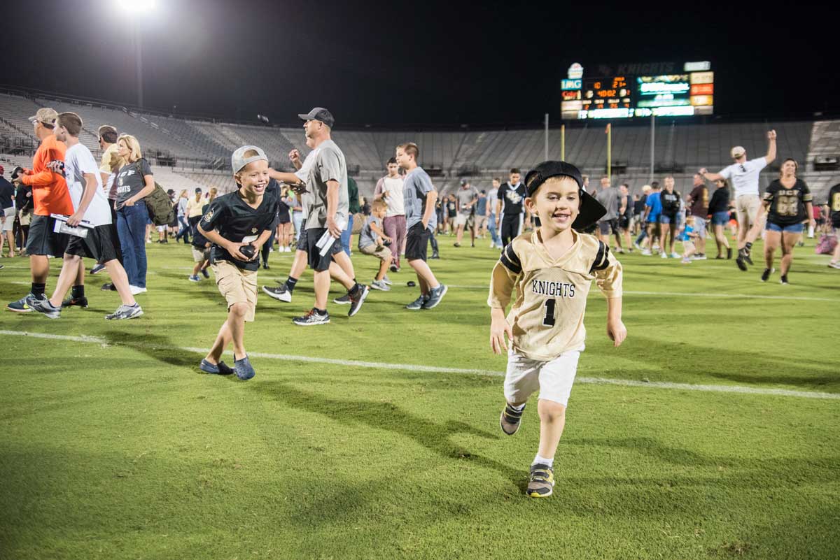 Children running on football field at night