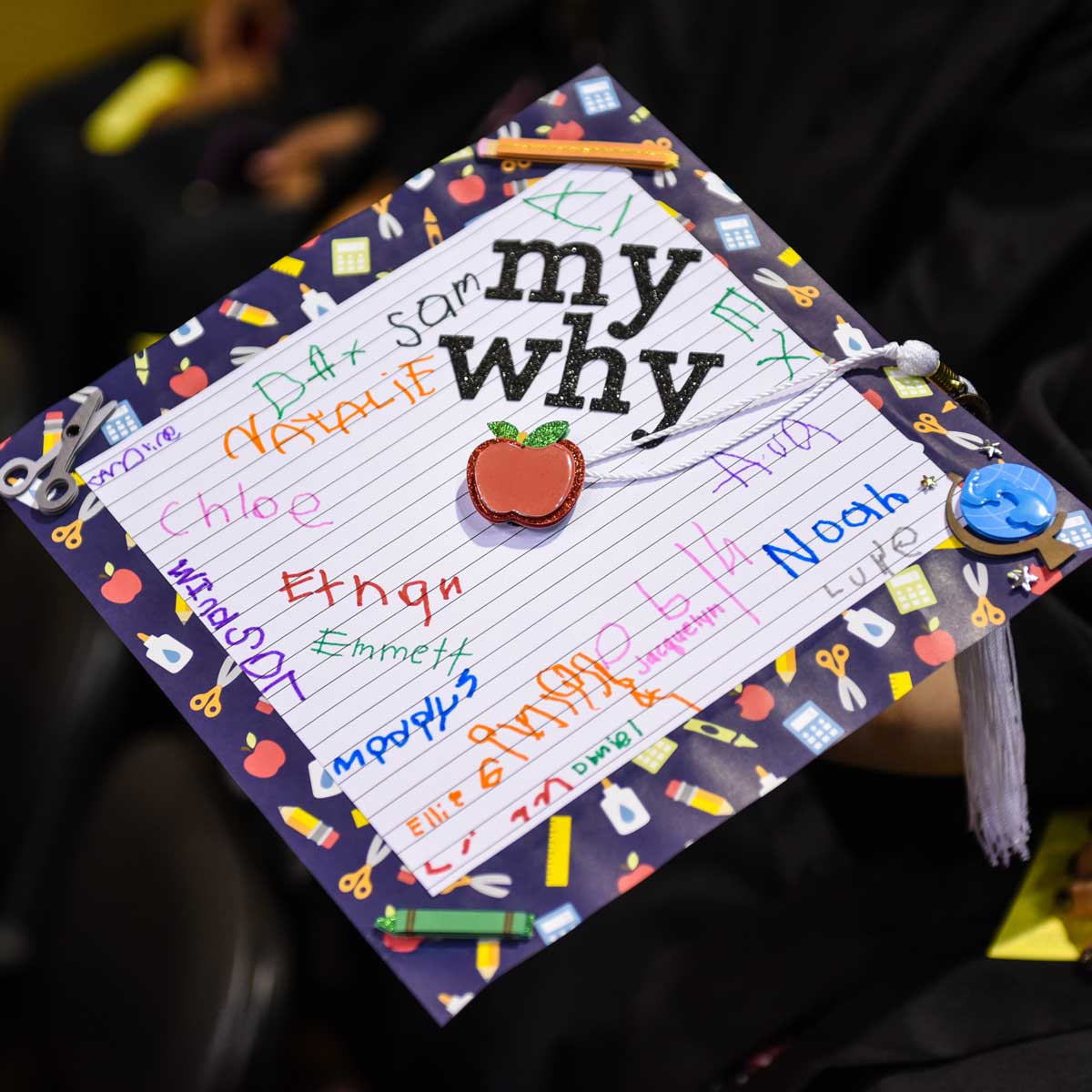 Grad cap decorated with children's signatures on notebook paper