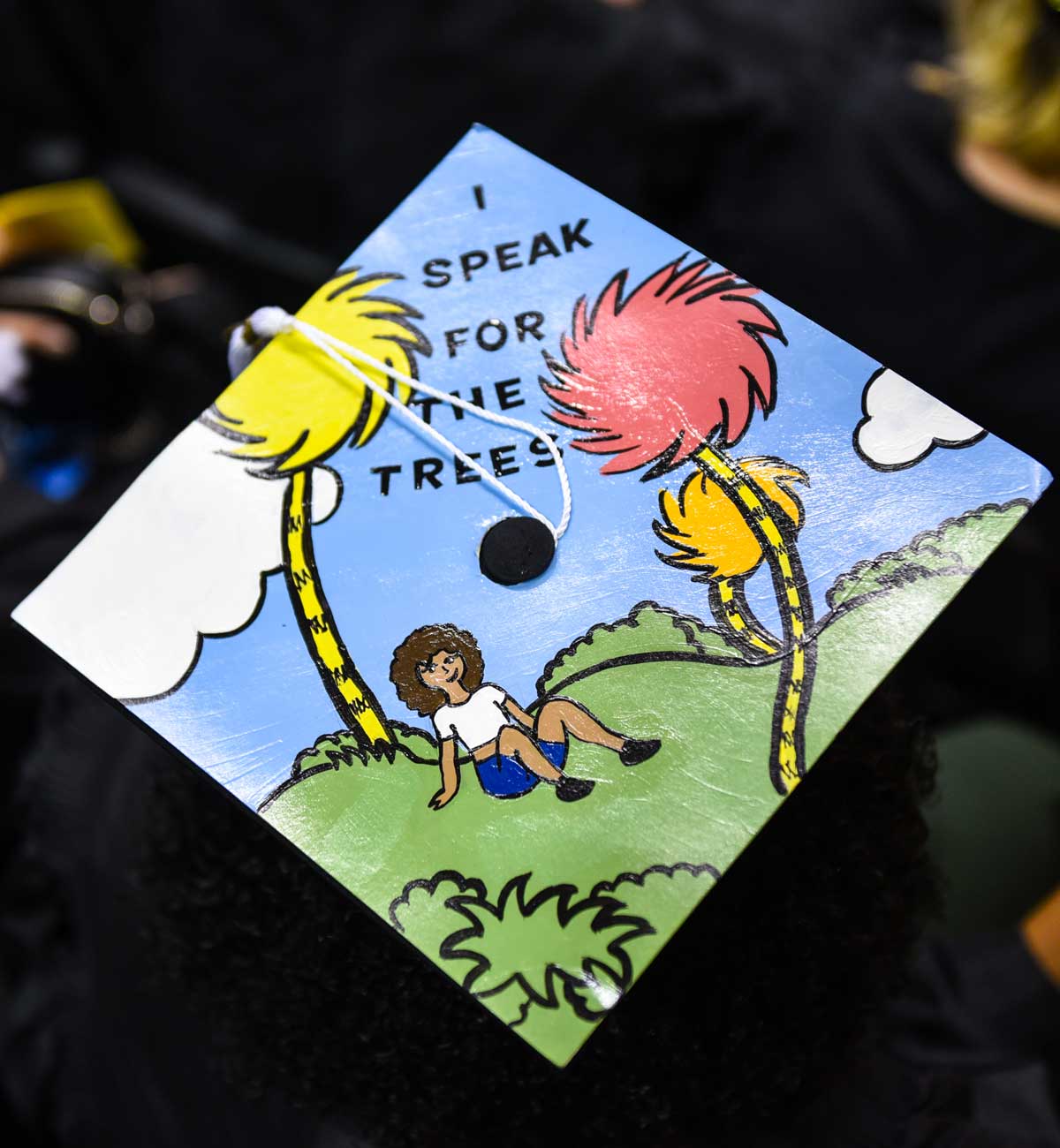 Grad cap decorated with text: I speak for the trees